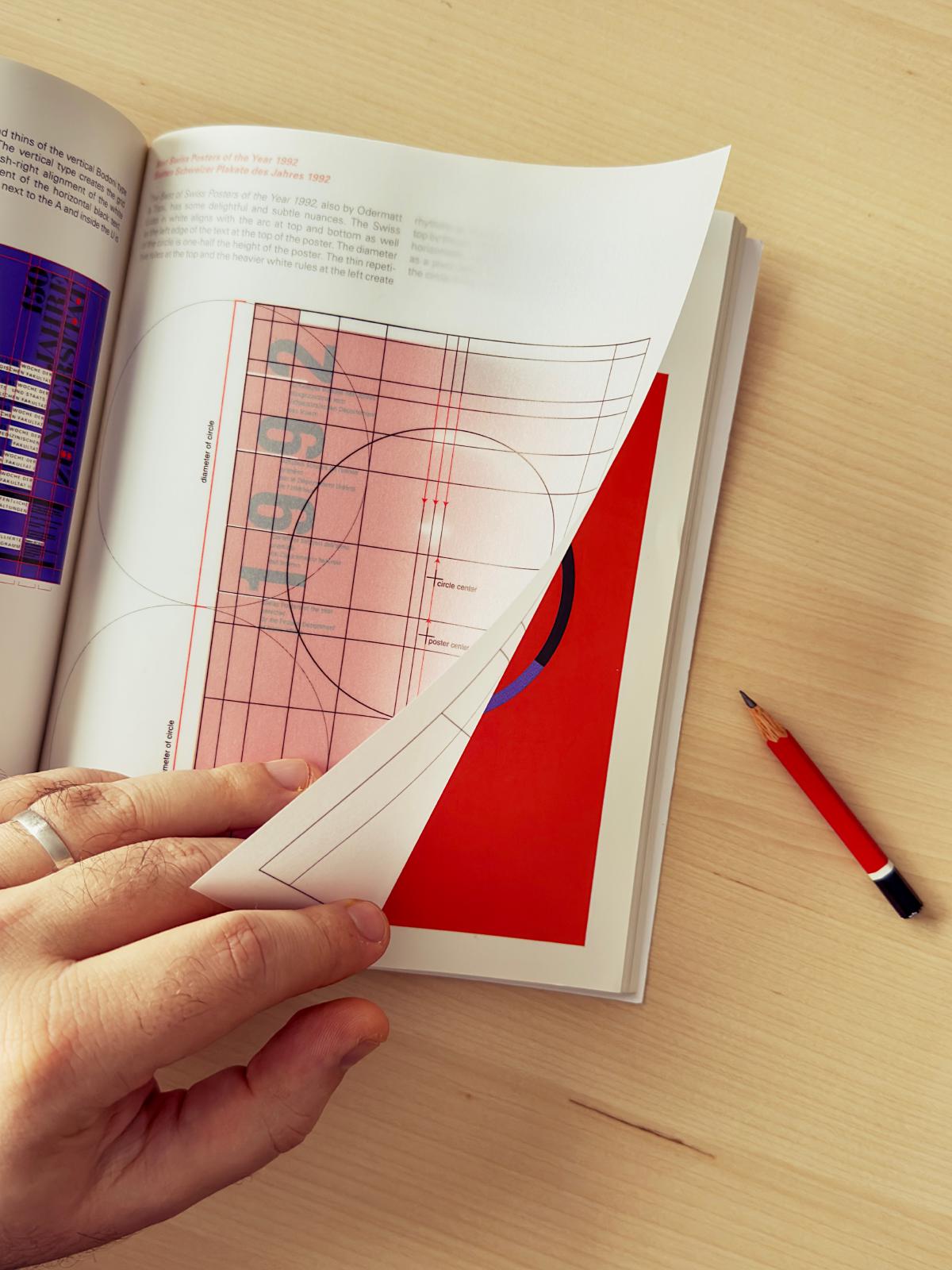 Une photographie verticale d’une main tournant une page du livre Grid Systems: Principles of Organizing Type